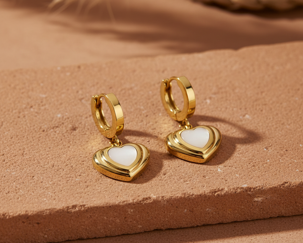 Gold open heart drop earrings flat lay on terracotta surface