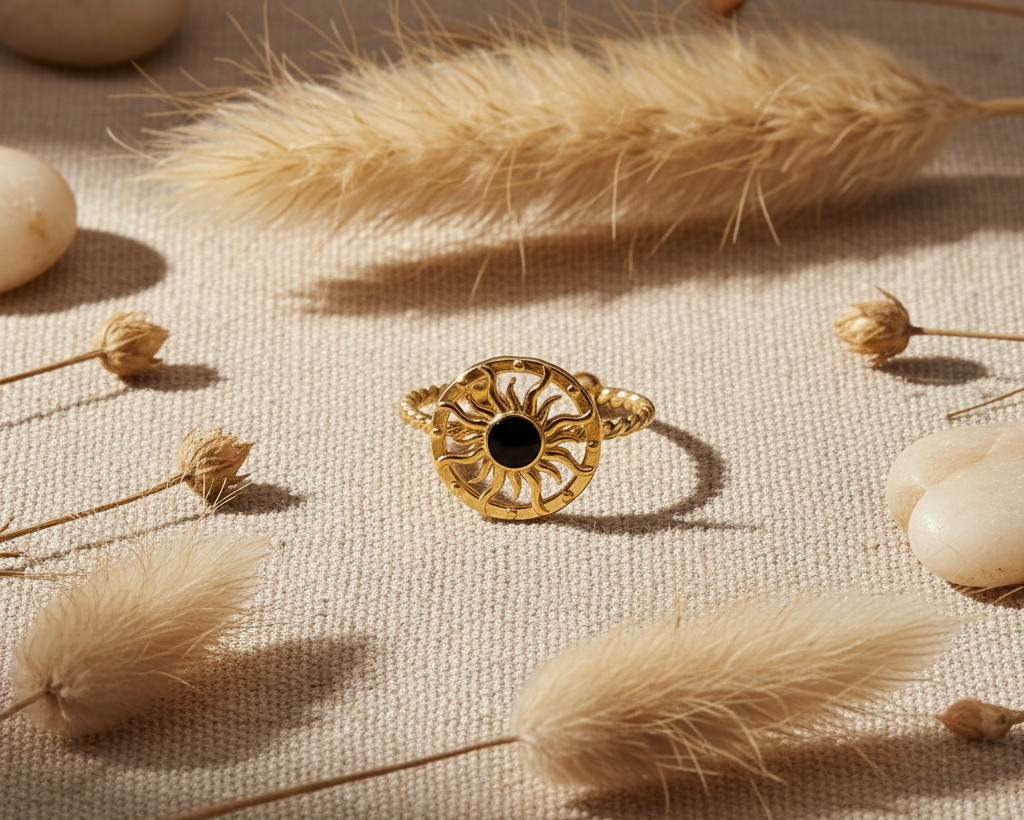 Gold sun ring with black stone centre on boho linen background