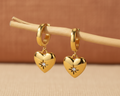 Gold heart huggie earrings on boho background