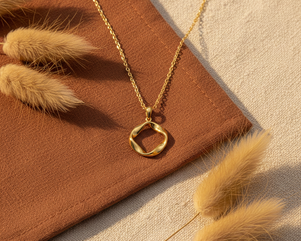 Gold Möbius circle pendant necklace on boho background with pampas grass and terracotta fabric