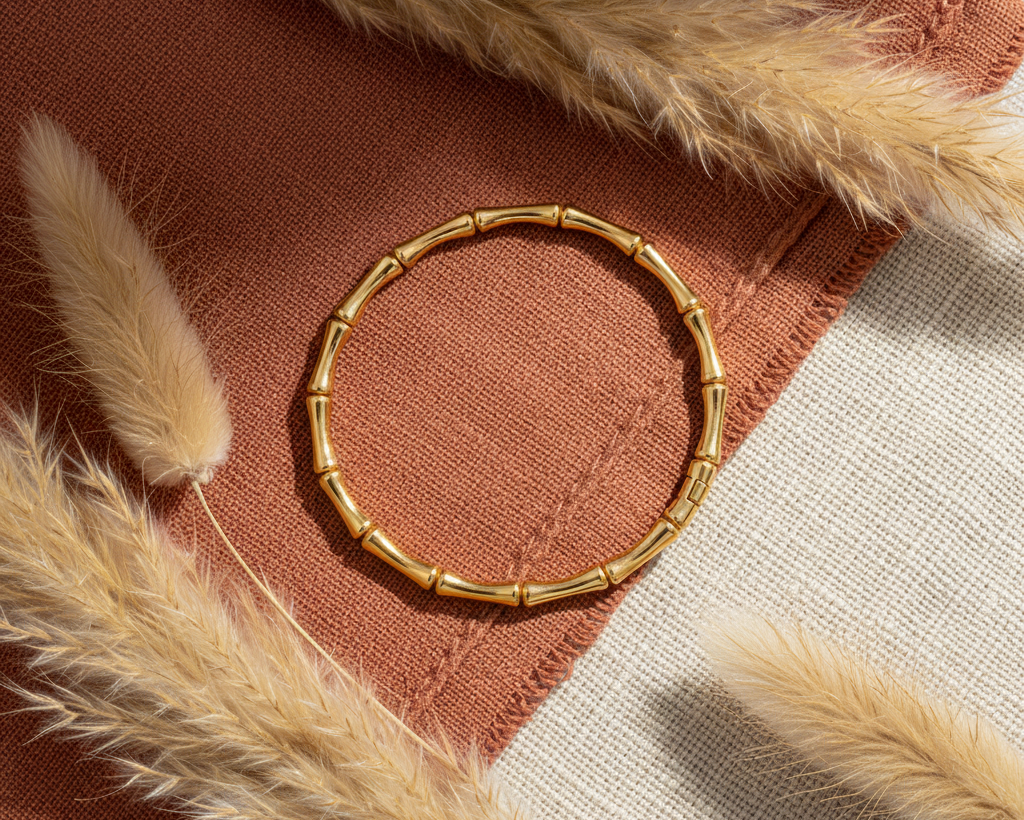 Gold bamboo bangle bracelet on boho background with pampas grass and terracotta fabric